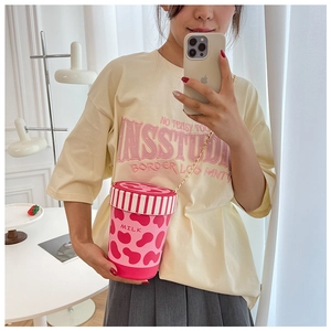 Detailansicht der rosa Milchkarton-Umhängetasche mit Kuhmuster und schicker Metallkette