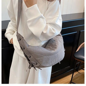 Detail of grey nylon crescent bag with corset-style drawstring ties and wide shoulder strap