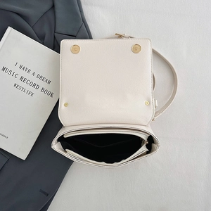 Top view of cream white shoulder bag showing multi-compartment accordion interior and gold buckles