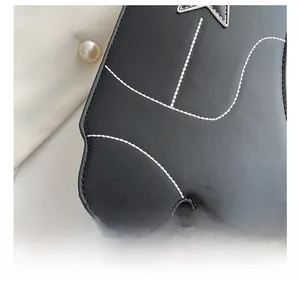 Gros plan sur le cuir noir avec coutures blanches et détail d'étoile du sac rétro