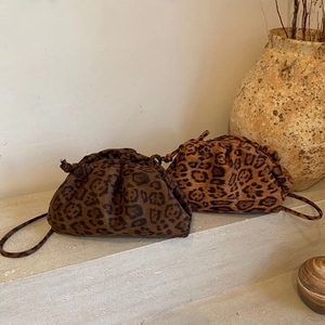 Leopard print cloud bags on stone steps with rustic vase in warm earth tones detail