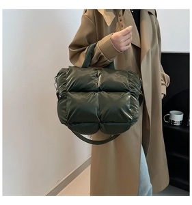 Détail d'un sac cabas matelassé vert foncé porté par un mannequin en trench-coat kaki
