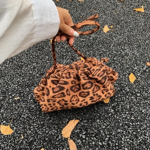 Leopard print velvet dumpling bag with drawstring and thin strap on a natural street background