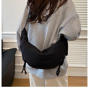Detail of black crescent crossbody bag with drawstring design and nylon texture