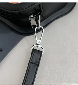 Dettaglio macro del gancio in metallo argento e cuciture sulla tracolla in pelle nera della borsa