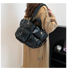Détail d'un sac cabas noir matelassé avec finition brillante et poignées rembourrées