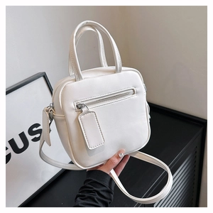 Detail of white minimalist square crossbody bag with dual handles and silver hardware