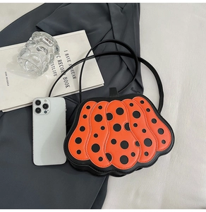 Dettaglio della borsa artistica a zucca arancione con pois neri e tracolla in pelle