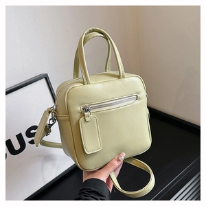 Detail view of avocado green crossbody bag showing dual handles and zipper pocket