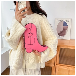 Détail d'un sac bandoulière rose en forme de botte avec motif étoile et chaîne en métal
