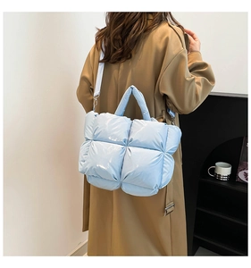 Sac fourre-tout bleu clair en nylon brillant avec motif matelassé porté par un mannequin