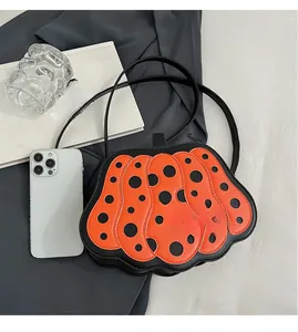 Dettaglio della borsa a zucca arancione con pois neri e sottile tracolla in pelle