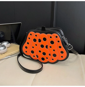Vista dettagliata della borsa a forma di zucca con pois neri e cerniera metallica robusta