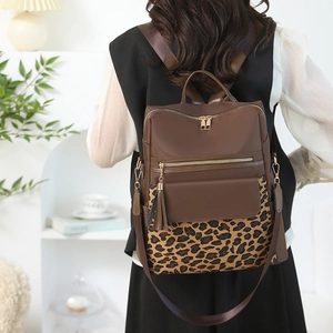 Rear view of a leopard print backpack with gold zippers and tassel detail on a female model