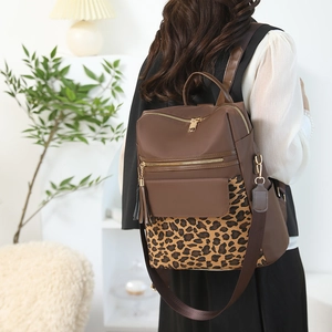 Detailed view of leopard print patchwork backpack with gold hardware and tassel decor