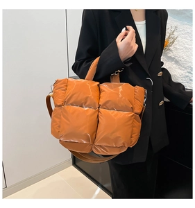 Détail d'un grand sac fourre-tout matelassé orange brillant avec une bandoulière réglable