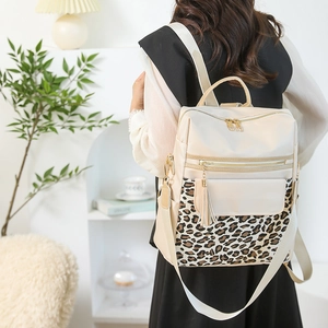 Detail of off-white leopard print backpack with gold zippers and tassel in a home setting