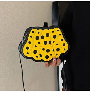 Dettaglio della borsa a tracolla gialla a forma di zucca con pois neri e tracolla fine
