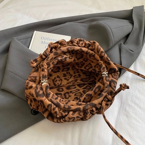 Detail of leopard print drawstring cloud bag placed on a grey blazer over white background