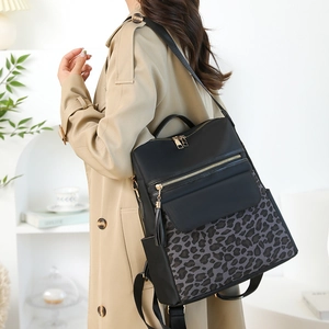 Detailed side view of leopard print backpack with gold zipper and black tassel charm