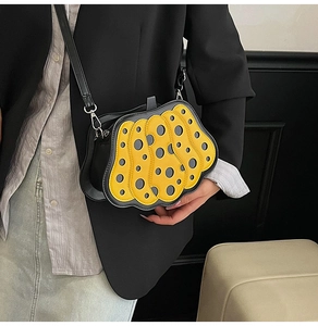 Dettaglio della borsa a zucca gialla con pois neri e tracolla in pelle di alta qualità