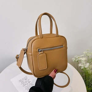 Minimalist caramel brown leather crossbody bag with top handles and front zipper pocket