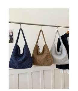 Detailed texture of plush hobo bags in dark blue, brown and light grey on a metal rack