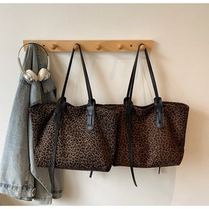 Detailed view of leopard print tote bags in light and dark brown on a wooden hook