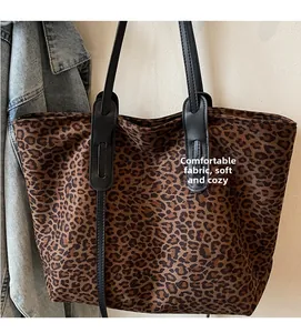 Detail showing the leopard print canvas texture and durable black shoulder strap of the tote