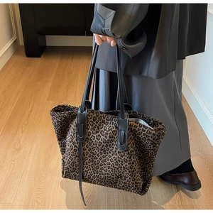 Close-up of leopard print fabric texture and dark brown leather straps on tote bag