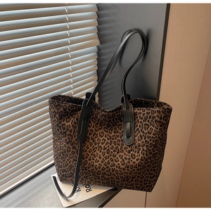 Detail of leopard print tote bag with black leather straps and premium fabric texture