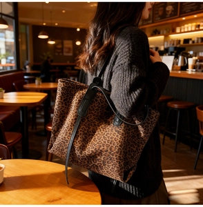 Detailed side view of the large leopard print tote bag with black leather shoulder straps