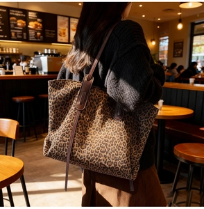 Detail of leopard print tote bag with brown leather straps in a bright cafe setting
