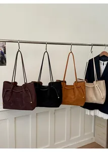 Detail of four multi-color suede tote bags with drawstring sides and gold metal beads