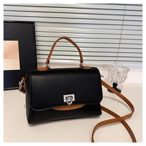 Detail of black textured leather handbag with brown handles and silver rotating lock
