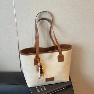 Vintage beige canvas tote bag with brown leather trim and colorful beaded pendant