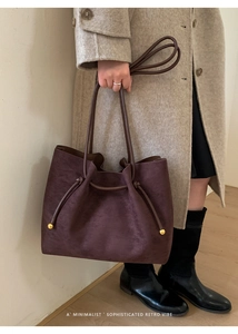 Detail of retro suede tote bag featuring unique knot strap and gold metal ball accents