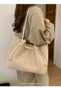 Detail of cream tote bag with suede texture, rope knot strap and golden metal beads
