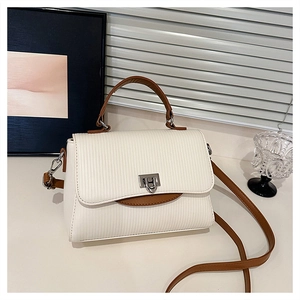 Detail of white textured crossbody bag with brown leather handles and silver buckle