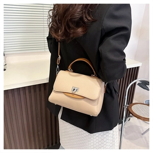 Detail of beige textured faux leather handbag showing elegant silver twist lock and stitching