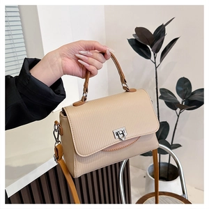 Detail of beige textured handbag showing silver metal lock and brown edge painting