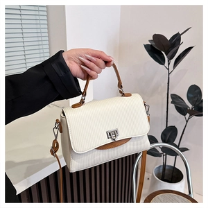 Close-up of textured ivory handbag with caramel trim and silver metallic buckle lock