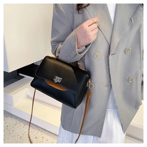 Detailed side view of black and brown leather crossbody bag with silver twist lock
