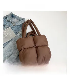 Detail shot of brown quilted tote bag with puffer design on white background