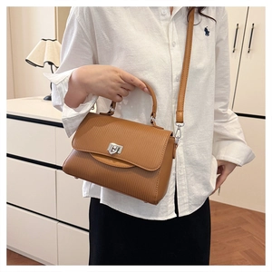 Detail of caramel brown pleated leather handbag showing silver buckle and top handle