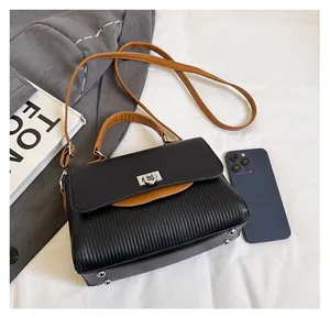 Close-up of textured black PU leather crossbody bag with brown handles and silver clasp