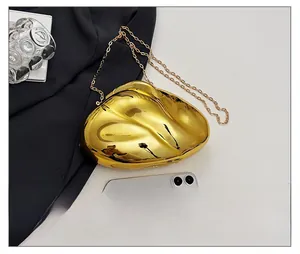 Detailed view of gold mirror metal clutch bag with chain and phone for size reference