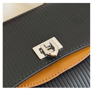Detail of silver twist lock on black textured and brown smooth leather shoulder bag