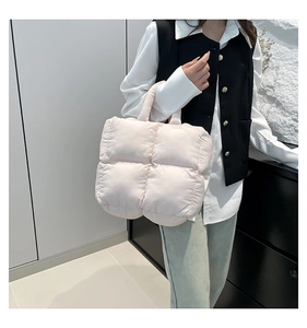 Quilted tote bag in cream white color carried by model in a minimalist interior setting