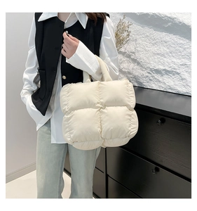 Detail of cream quilted tote bag with soft padded texture and minimalist shoulder handle